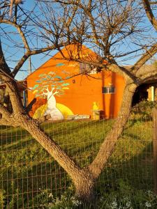 ein orangefarbenes Gebäude mit einem Baum davor in der Unterkunft De Sol a Sol in Barra de Valizas