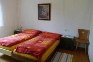 1 dormitorio con 1 cama con sábanas rojas y silla en Akalei, en Aeschi
