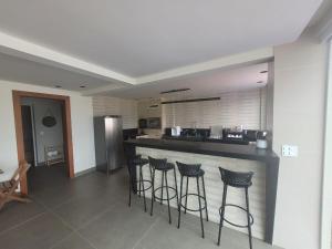 a kitchen with a bar with four bar stools at SKYHOUSE BOUTIQUE - Loft & SPA - piscina aquecida e sauna privativa - Centro, Domingos Martins in Domingos Martins