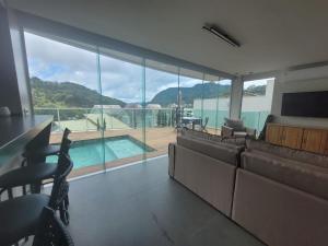 a living room with a couch and a television and a pool at SKYHOUSE BOUTIQUE - Loft & SPA - piscina aquecida e sauna privativa - Centro, Domingos Martins in Domingos Martins