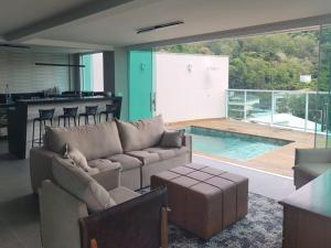 a living room with a couch and a kitchen and a pool at SKYHOUSE BOUTIQUE - Loft & SPA - piscina aquecida e sauna privativa - Centro, Domingos Martins in Domingos Martins