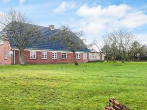 a red brick house with a large grassy field at 5 person holiday home in Rømø in Toftum