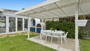een witte pergola met een tafel en stoelen eronder bij La Plage Portsea in Portsea