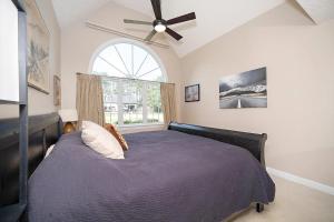 Un dormitorio con una cama con ventilador de techo y una ventana. en Majestic Home in Summer Oaks, en Apex