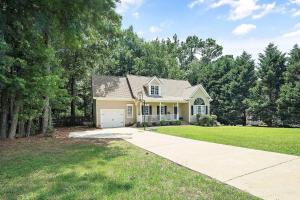 Majestic Home in Summer Oaks في أبيكس: منزل أصفر صغير مع ممر سيارات وأشجار