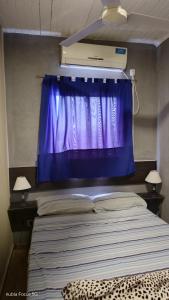 une chambre avec un rideau violet et un lit dans l'établissement Lo de Andrés y Marina, à Arroyo de Los Patos