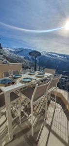 a table with wine glasses and an umbrella on a balcony at SnowGranada Los Valles Daniela House in Monachil