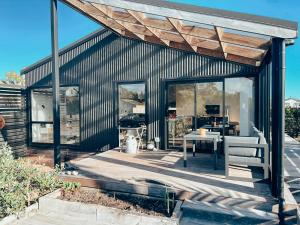a house with a deck with a table and chairs at Kowhai Cabin - Serene Scandi Escape in Hokitika in Hokitika