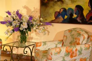 un vaso di fiori su un tavolo di vetro accanto a due sedie di Hotel Isabella a Taormina
