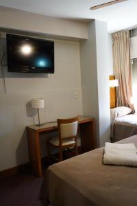 a hotel room with a desk and a tv on the wall at Hotel coventry in Santiago del Estero