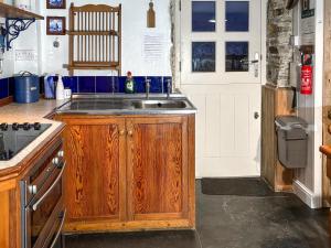 a kitchen with a sink next to a door at Downhouse Cottage in Delabole