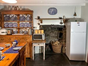 a kitchen with a refrigerator and a table with a microwave at Downhouse Cottage in Delabole