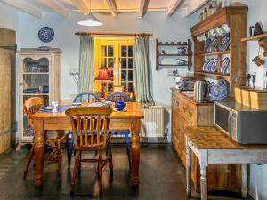 a dining room with a wooden table and chairs at Downhouse Cottage in Delabole