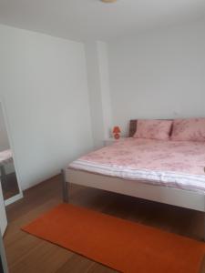 a bedroom with a bed with pink sheets and a orange rug at Charmante Wohnung Adriana F in Dobreć