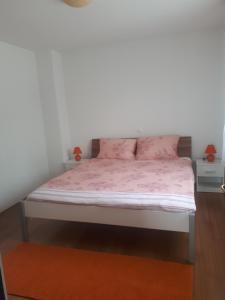 a bedroom with a bed with pink sheets and pink pillows at Charmante Wohnung Adriana F in Dobreć +5 photos