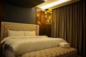 a bedroom with a large white bed with a bench at Goldcrest Alfatah Mall - DHA Phase 4 - Luxury Apartments by Alvis Suite in Lahore