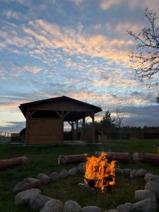 a fire pit in a field with a gazebo at Agroturystyka AKPólko in Biała Podlaska