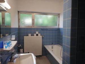 ein blau gefliestes Bad mit einer Badewanne und einem Waschbecken in der Unterkunft Appartement in Ruhbank mit Garten und Terrasse in Pirmasens