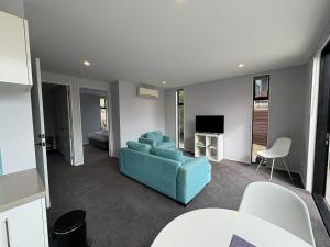 Una sala de estar con un sofá azul y un televisor. en Glenvue 2 Bed, en Lake Tekapo