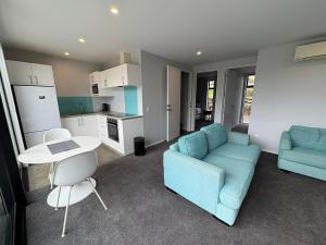 Una sala de estar con un sofá azul y una mesa. en Glenvue 2 Bed, en Lake Tekapo