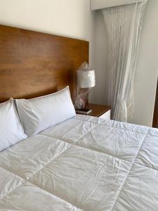 ein Bett mit weißen Laken und einem hölzernen Kopfteil in der Unterkunft Monterrico Villa salida a Piscina y Jardin in Monterrico + 8 Fotos