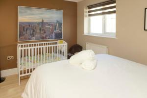 un berceau blanc dans une chambre avec un tableau sur le mur dans l'établissement Brecon Beacons Welsh Countryside Home, à Merthyr Tydfil