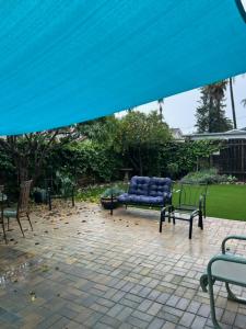 圣巴巴拉Goodland Green House的庭院设有2张长椅和1把蓝色椅子