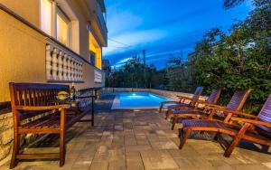 un groupe de chaises assises à côté d'une piscine dans l'établissement Familienpension Tina Appartement 7, à Šilo