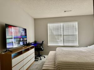 Schlafzimmer mit einem Bett, einem Schreibtisch und einem Flachbild-TV in der Unterkunft A private master room in modern complex shared apartment in Lawrenceville 