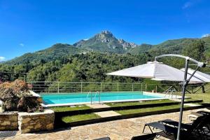une piscine avec un parasol et une montagne dans l'établissement Ferienhaus In Vergemoli Mit Schönem Kamin, à Vergemoli