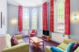 Una sala de estar con cortinas rojas y chimenea. en Pilcher Gate House, en Nottingham