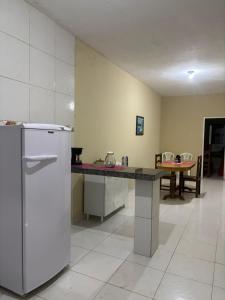a kitchen with a counter and a refrigerator and a table at Casa de temporada in Tianguá