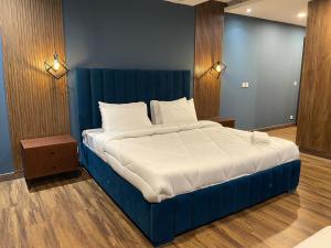 a blue bed with white sheets and pillows in a room at Gold Crest Mall Luxury Apartments with Balcony by NestNow in DHA Phase 4 Lahore in Lahore