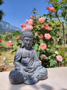 a statue of a buddha in front of pink roses at Ferienhaus In Thasos Mit Großer Terrasse in Potamia