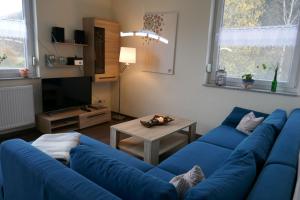 ein Wohnzimmer mit einem blauen Sofa und einem Tisch in der Unterkunft moderne Ferienwohnung " Ober Langengarten" mit separatem Wellnessbereich, direkt am Radweg in Pittenbach