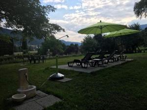 - une rangée de chaises et un parasol dans un parc dans l'établissement Ferienhaus In Steindorf Am Ossiacher See, à Steindorf am Ossiacher See 15 autres photos