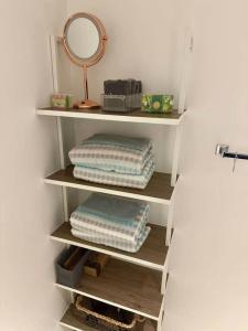 ein Regal mit Handtüchern und einem Spiegel im Bad in der Unterkunft Cozy King Suite w/Coffee Bar + Walkable to Mass St in Lawrence + 2 Fotos