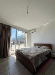 ein Schlafzimmer mit einem Bett und einem großen Fenster in der Unterkunft Mountain View Apartment in the heart of city in Peja