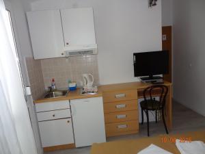 a small kitchen with a sink and a desk with a television at Komfortables Studio Apartment Mit Meerblick in Živogošće