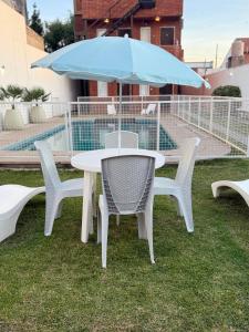 einen Tisch und Stühle mit einem Regenschirm auf dem Rasen in der Unterkunft Hotel Punta Lavalle in San Luis
