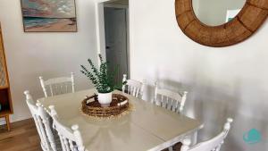 ein weißer Esstisch mit einer Topfpflanze darauf in der Unterkunft Barefoot at Blacksmiths Beach in Blacksmiths