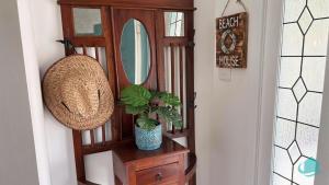 ein Spiegel und eine Pflanze auf einer Kommode in einem Flur in der Unterkunft Barefoot at Blacksmiths Beach in Blacksmiths