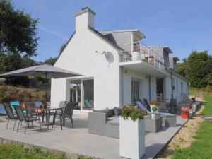 a white house with a patio with a table and chairs at Holiday home with partial sea view, Douarnenez in Tréboul