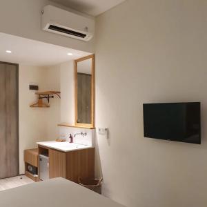 ein Badezimmer mit Waschbecken und einem Fernseher an der Wand in der Unterkunft Lenarda hotel in Nggorang