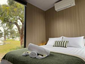 um quarto com uma cama com toalhas e uma janela em Bush Hideaway X at Tiny Away em Glenroy