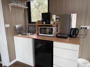 uma cozinha com um balcão com um micro-ondas e um lavatório em Bush Hideaway X at Tiny Away em Glenroy