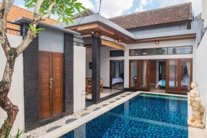 a villa with a swimming pool in front of a house at Tranquil 2BR Villa, Near Canguu and Pererenan in Tumbak Bayuh