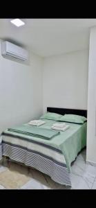 ein Bett in einem weißen Zimmer mit einer grünen Decke in der Unterkunft Casa aconchegante e bem localizada - São Brás in Belém