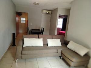 a living room with a brown couch and white pillows at Bonaterra in El Jobo