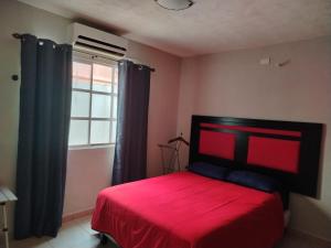 a bedroom with a red bed and a window at Bonaterra in El Jobo